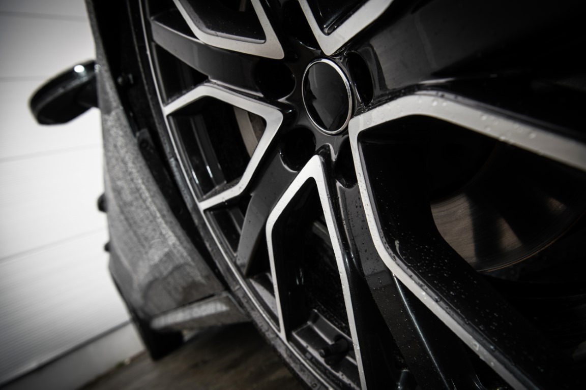 Modern Aluminium Car Alloy Wheel Ground Level Close Up Photo. Automotive Industry Theme.