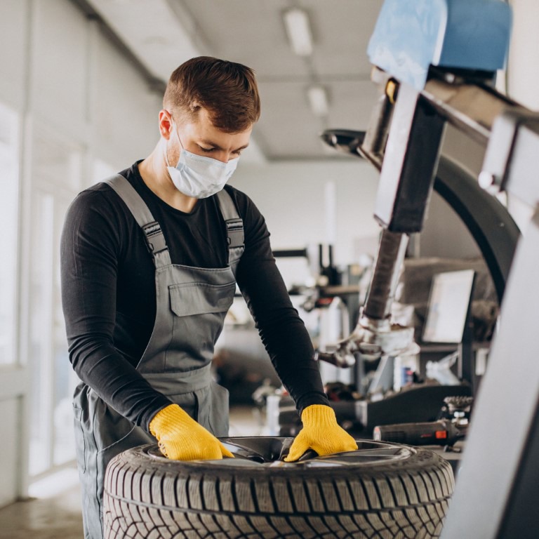 Car mechanic changing wheels in car