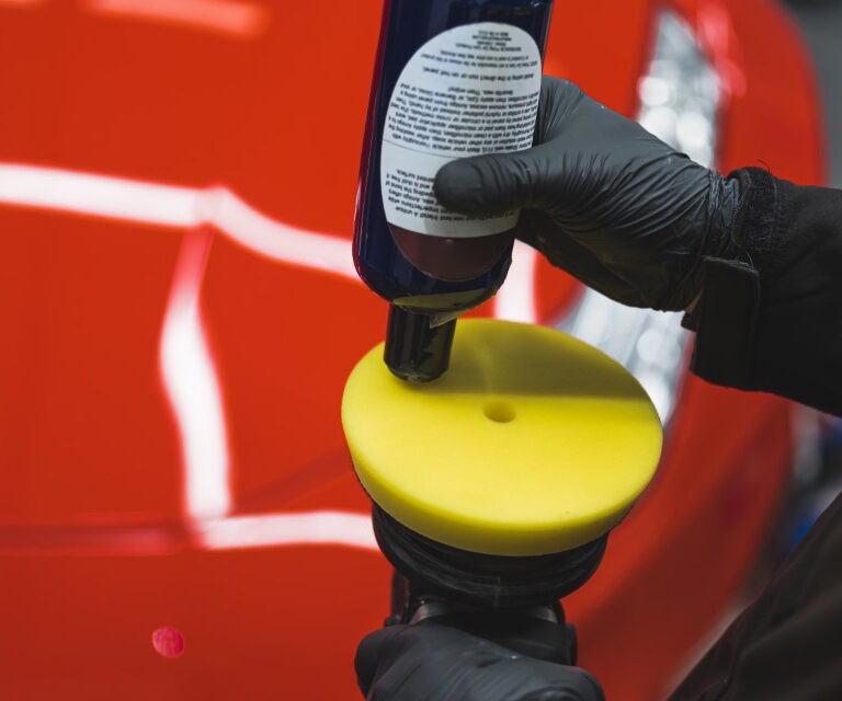 closeup shot of a mechanic adding liquid on an orbital polisher to use on a car at the repair shop. High quality photo